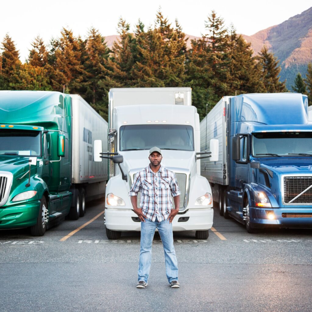 Black man truck driver near his truck parked in a parking lot at a truck stop