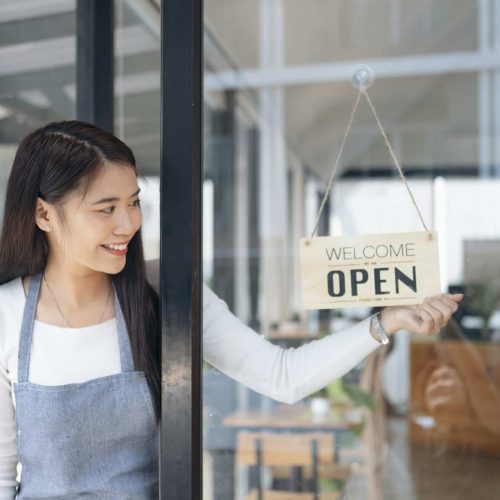 Close up of woman hands holding sign now we are open support local business.