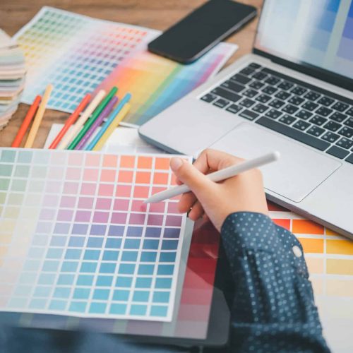 Graphic designer architects who work with laptops and color comparison tables for design work.